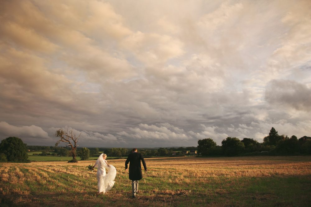 photo of a bride and groom in a field at sunset.