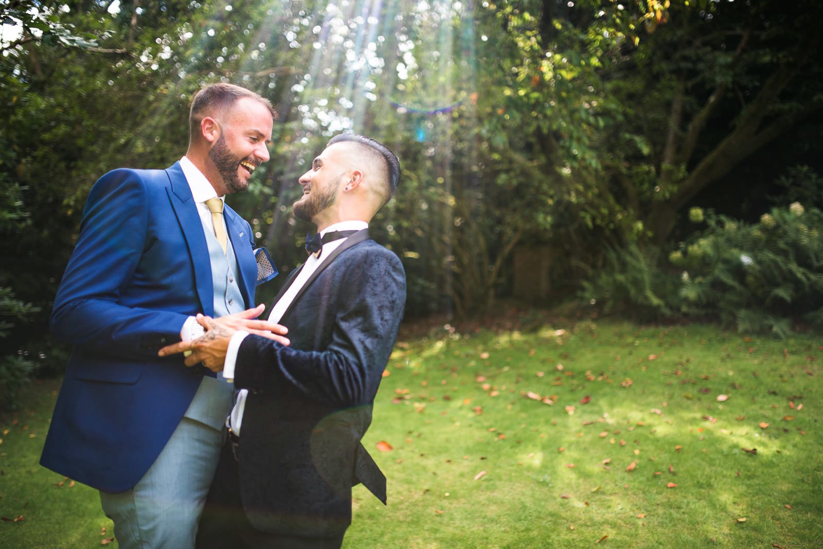 Stylish wedding photography for a same sex Summer wedding featuring the grooms laughing and cuddling together.