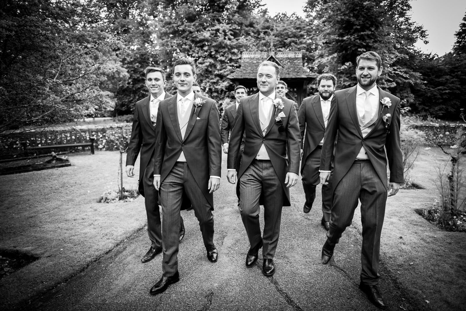 Black and white documentary image of the groom and his grooms party walking to church.