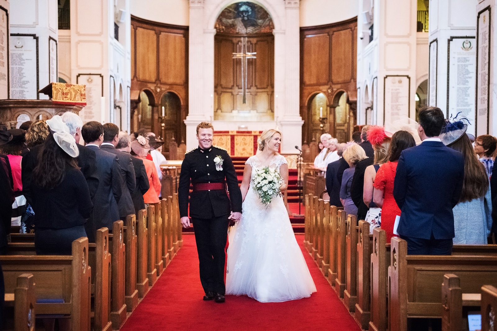 A bride and groom walk back down the aisle of the military chapel at Sandhurst academy.