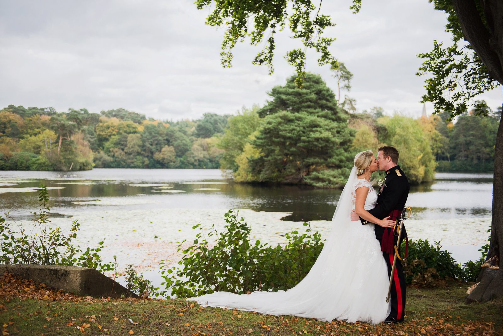 Bride and groom portraits by the lake in the grounds of the Royal Military Academy Sandhurst for their September wedding.