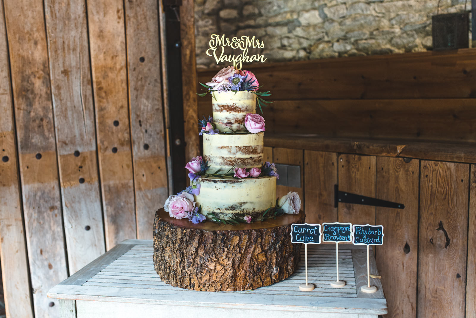 Rustic naked wedding cake decorated in real flowers for a barn wedding.