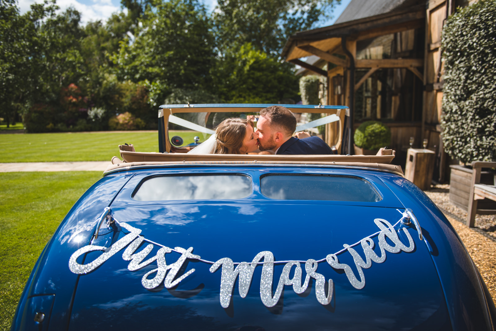 The bride and groom photographed in their vintage blue wedding car.